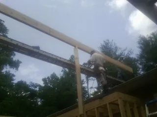 Carpenter setting a ridge beam over a new addition frame — Ice Dam Removal by Roofing Brothers in Conley