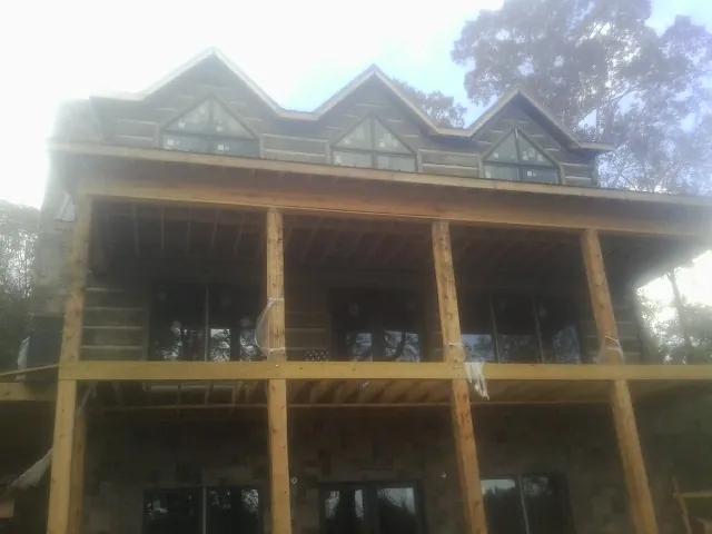 Dormers and porch framing on a large log home under construction — Roof Coating work by our crew in Conley