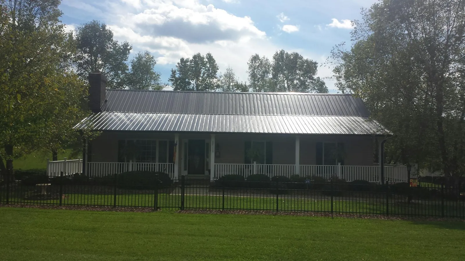 Gray metal roof on a brick ranch with a full width front porch — Gutter Guard Installation work by our crew in Conley