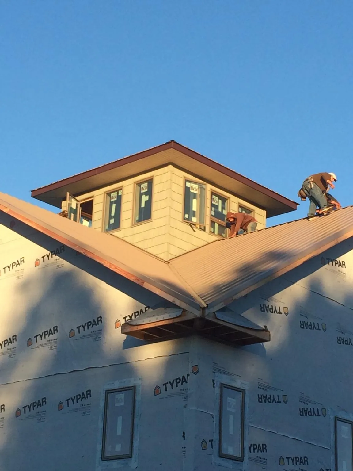 Roofers working around a rooftop cupola on a new metal roof at sunset — Roof Waterproofing in Conley by Roofing Brothers